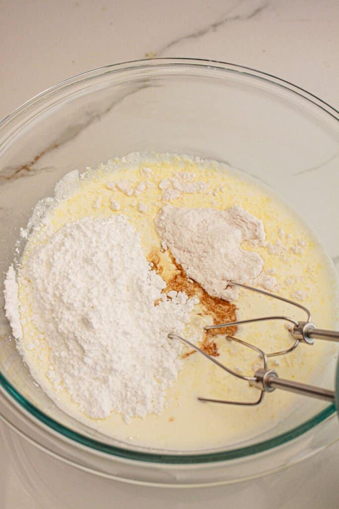 Frosting being mixed in a glass mixing bowl.
