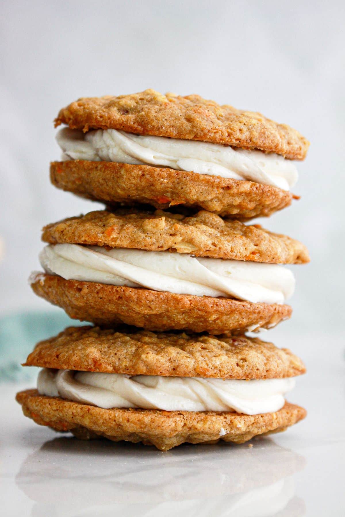 Three carrot cake sandwich cookies stacked on top of each other.