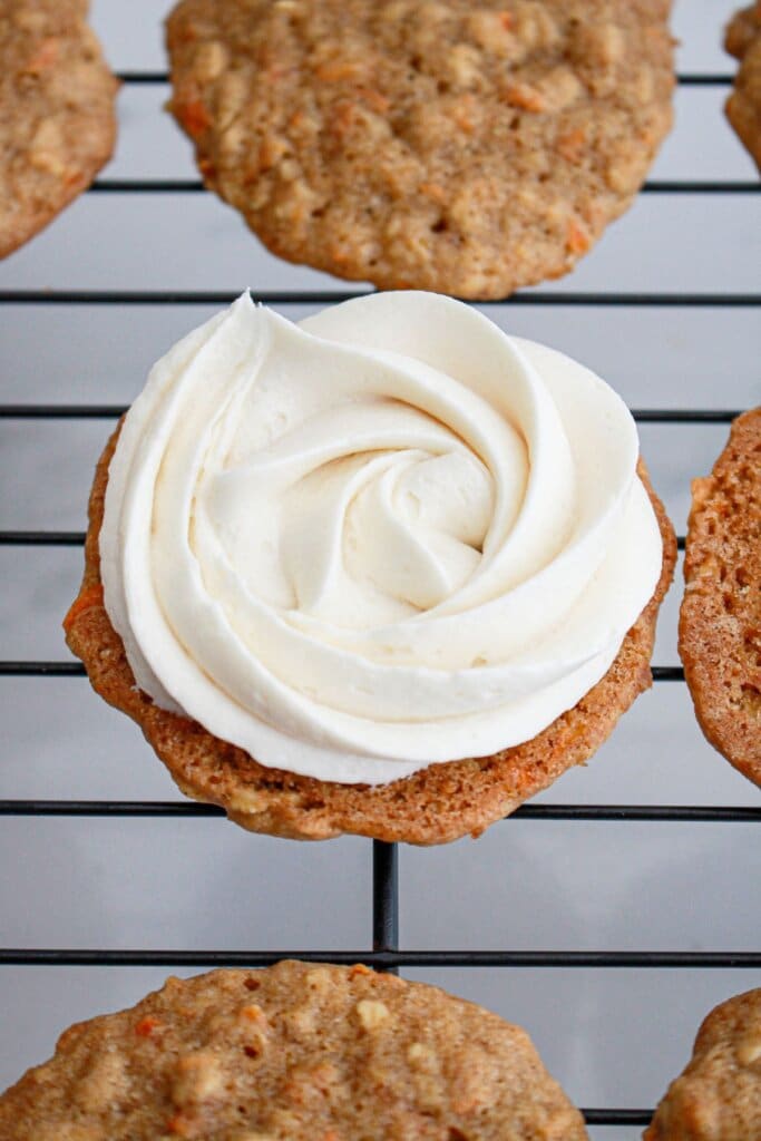 Cream cheese frosting being added to the top of a cookie.