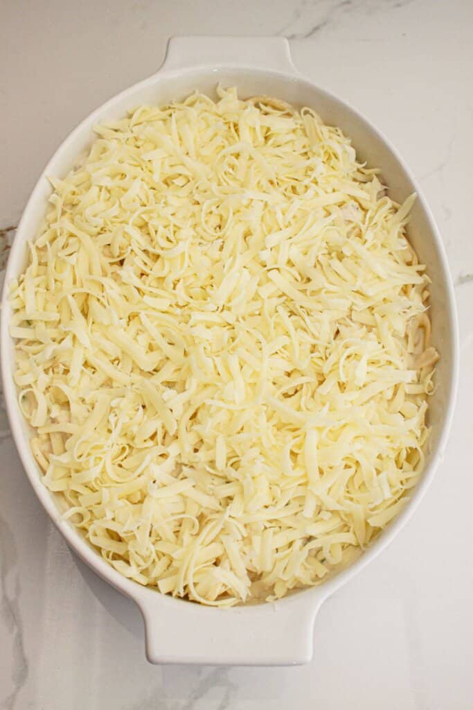 Mozzarella cheese being sprinkled on top of a casserole dish.