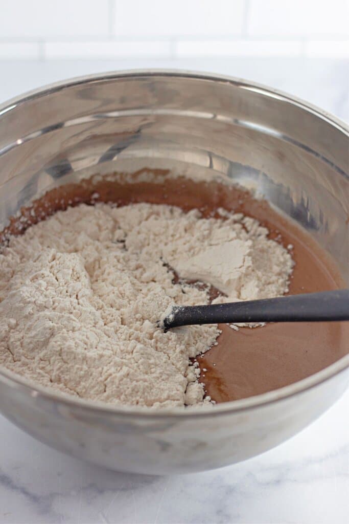 Dry ingredients being added to wet ingredients in a mixing bowl.