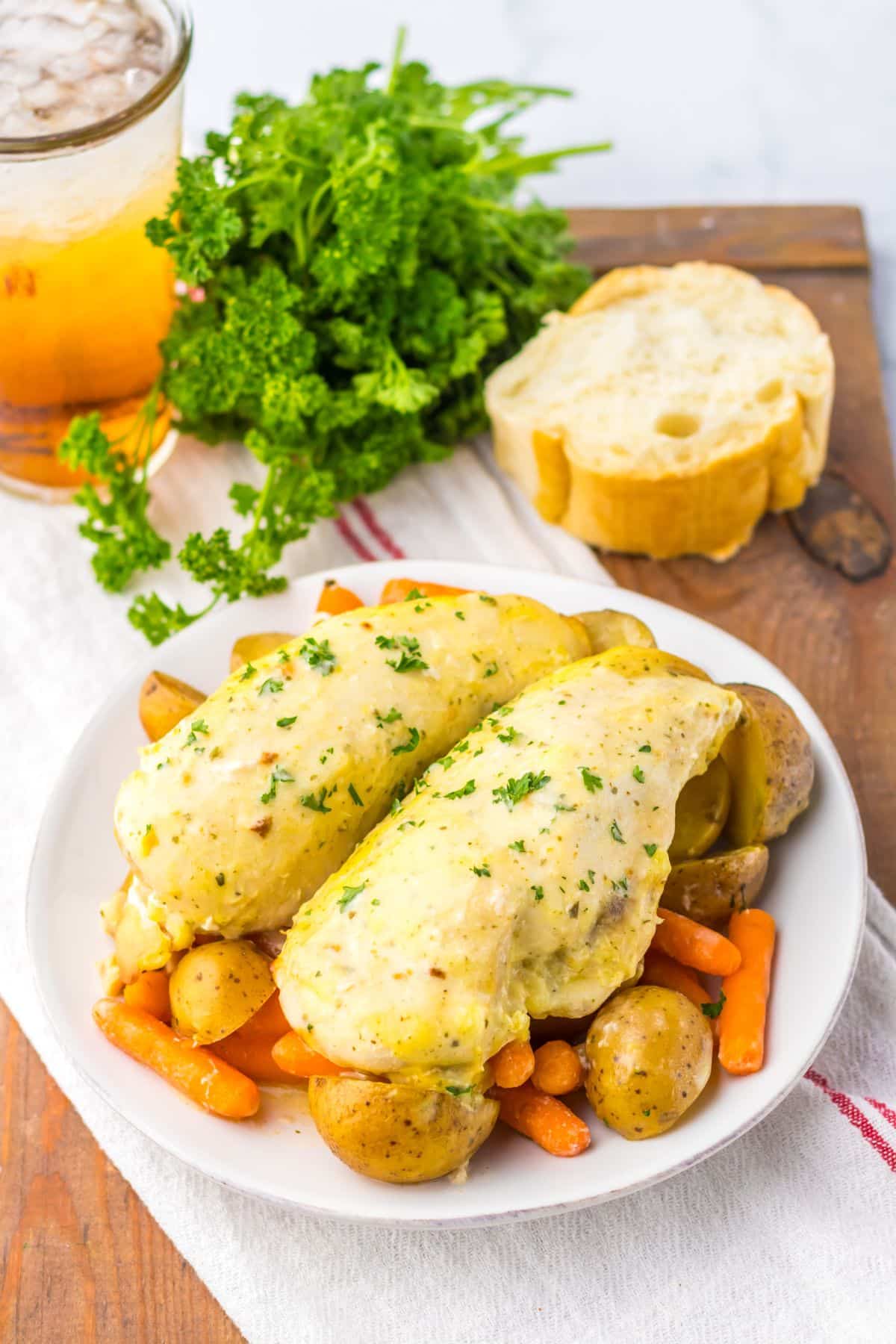 Plate full of creamy ranch chicken on top of a bed of potatoes and carrots.