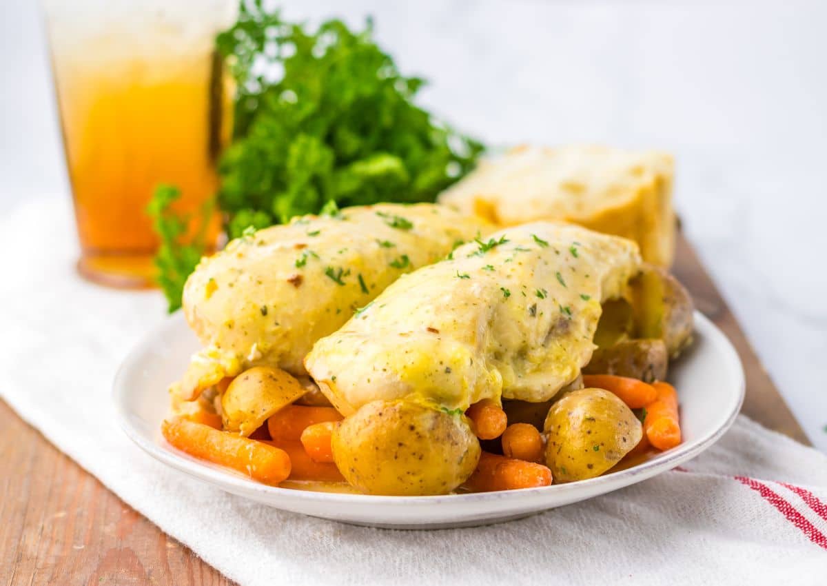 Plate full of creamy ranch chicken on top of a bed of potatoes and carrots.