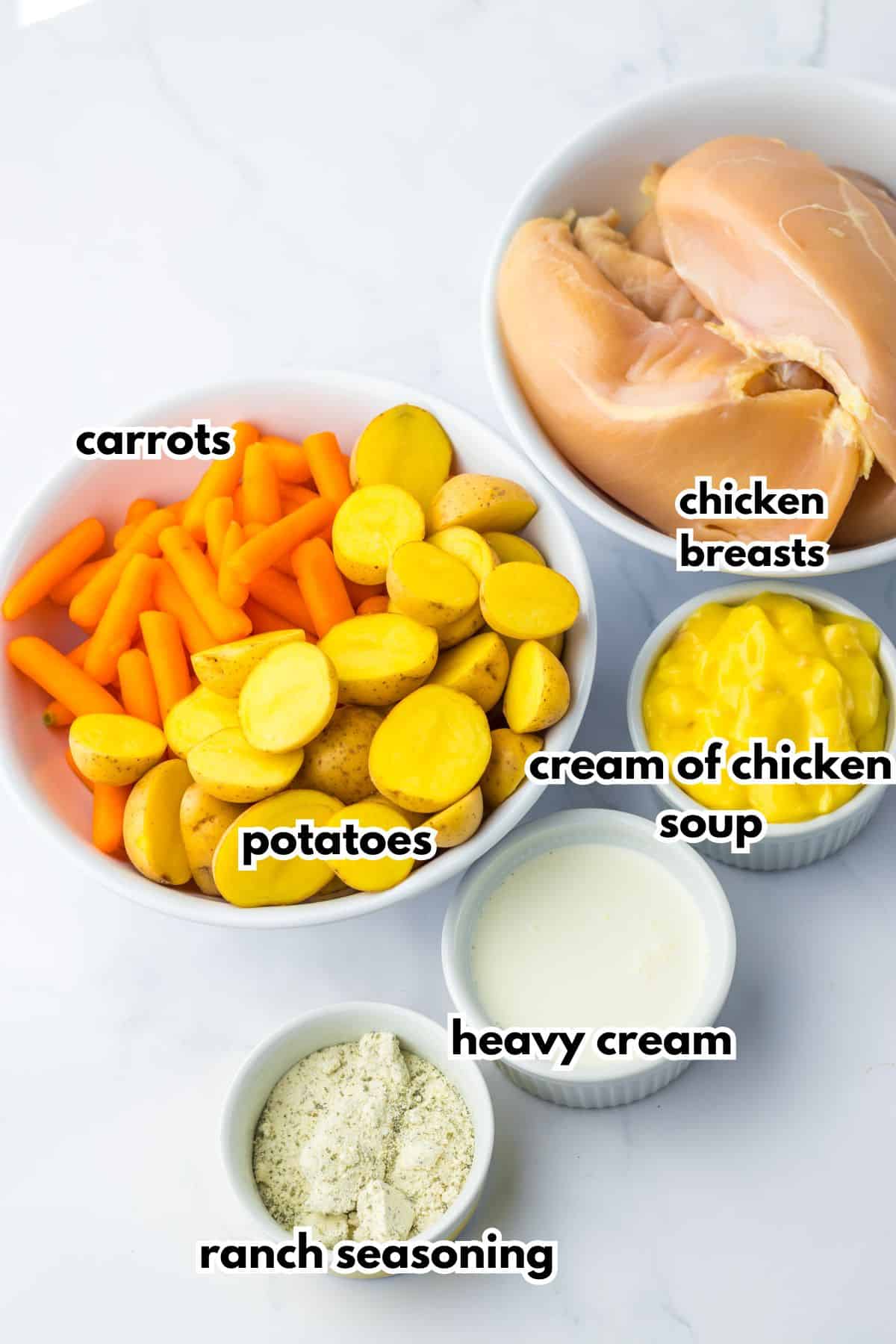 Bowls of carrots, potatoes, cream of chicken soup, chicken breasts, heavy cream, and seasoning mix.
