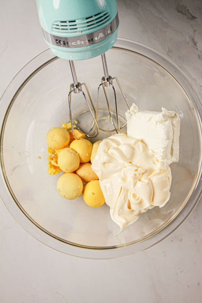 Yolks, mayo, and cream cheese in a glass mixing bowl.
