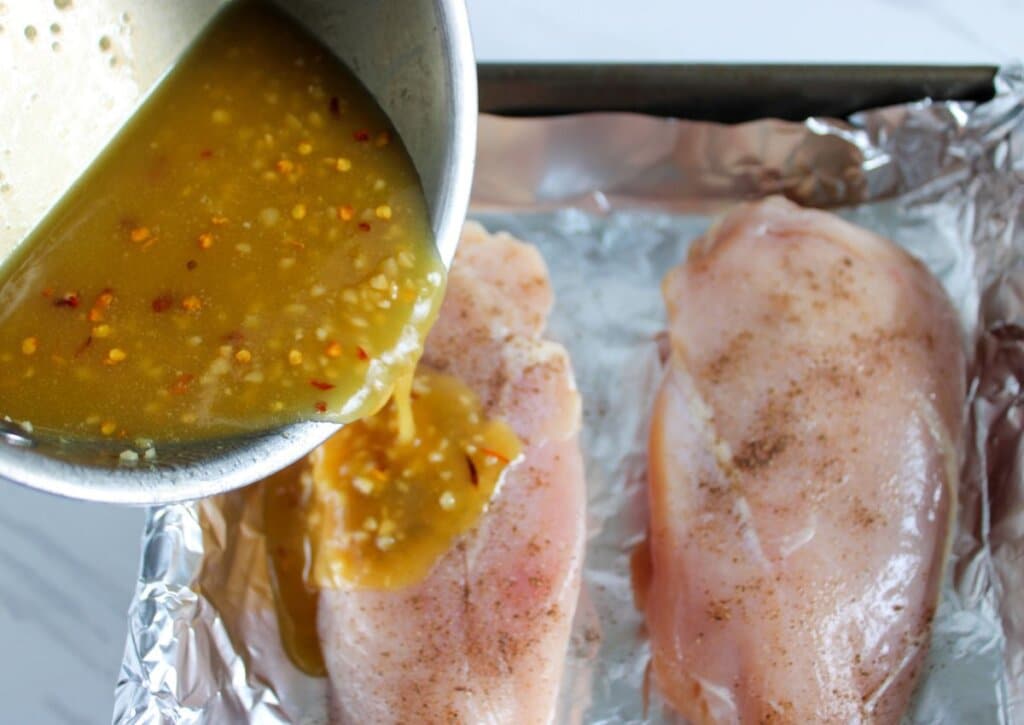 Sauce being pourted over meat in a baking dish.