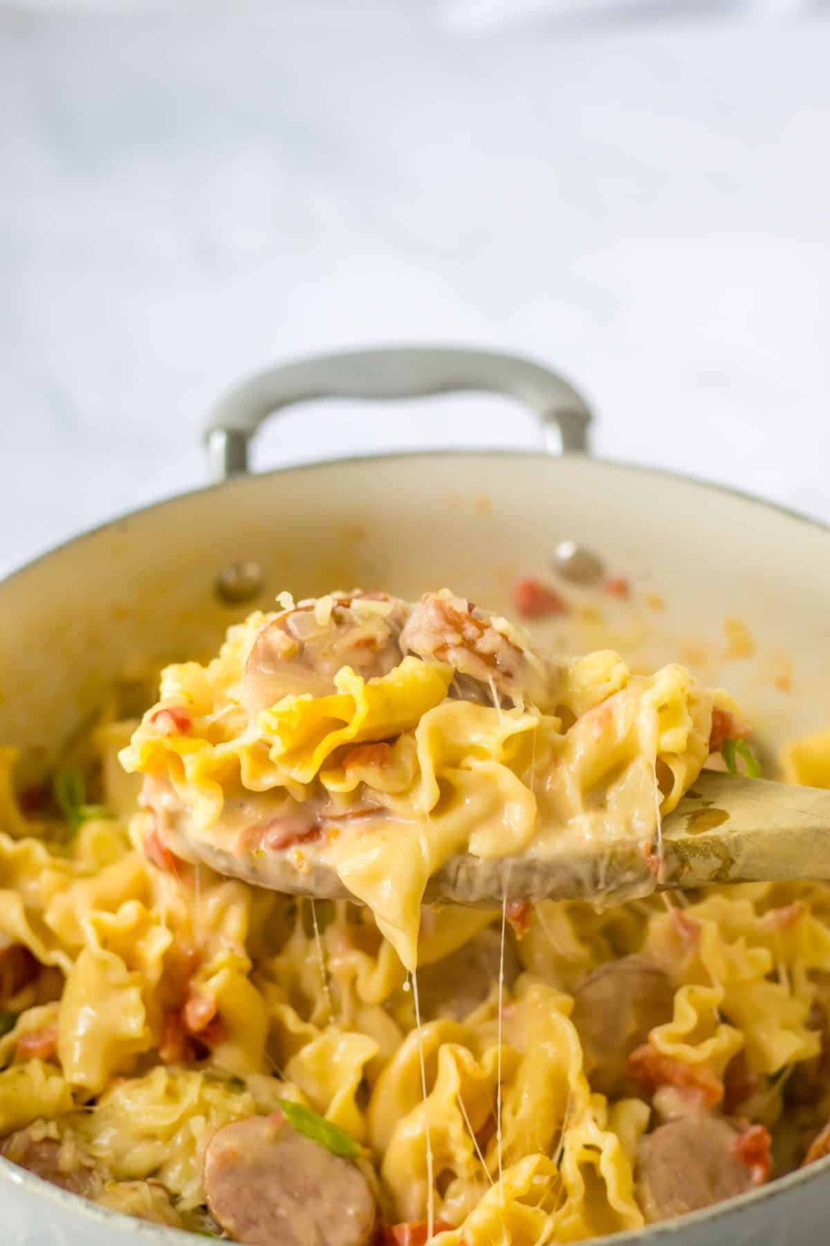 Wooden spoon full of one pot sausage pasta.