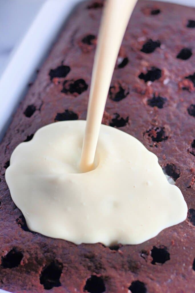 Condensed milk being poured on top of cake.