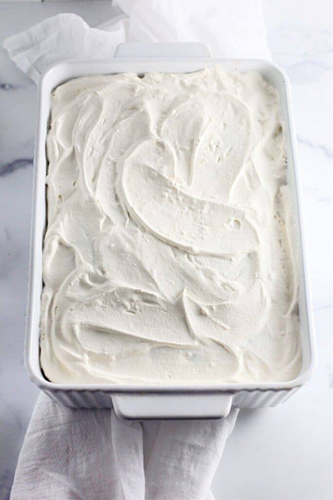 Cool Whip being spread on top of cake.