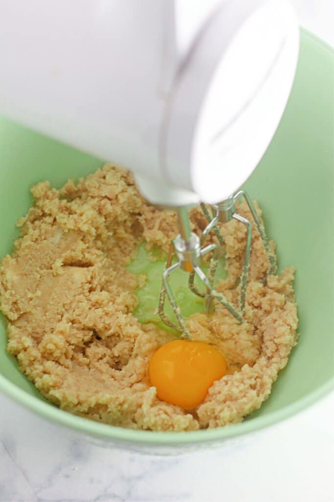 Egg being mixed into dough in a mixing bowl.