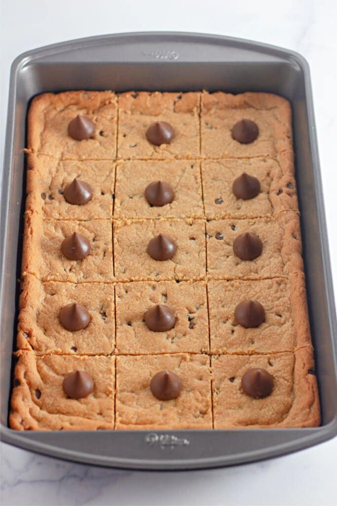 Peanut butter bars topped with a kiss in a baking pan.
