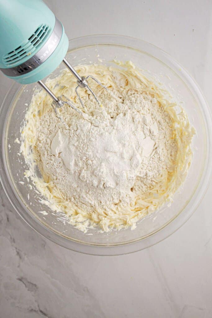 Flour being added to dough in a glass mixing bowl.