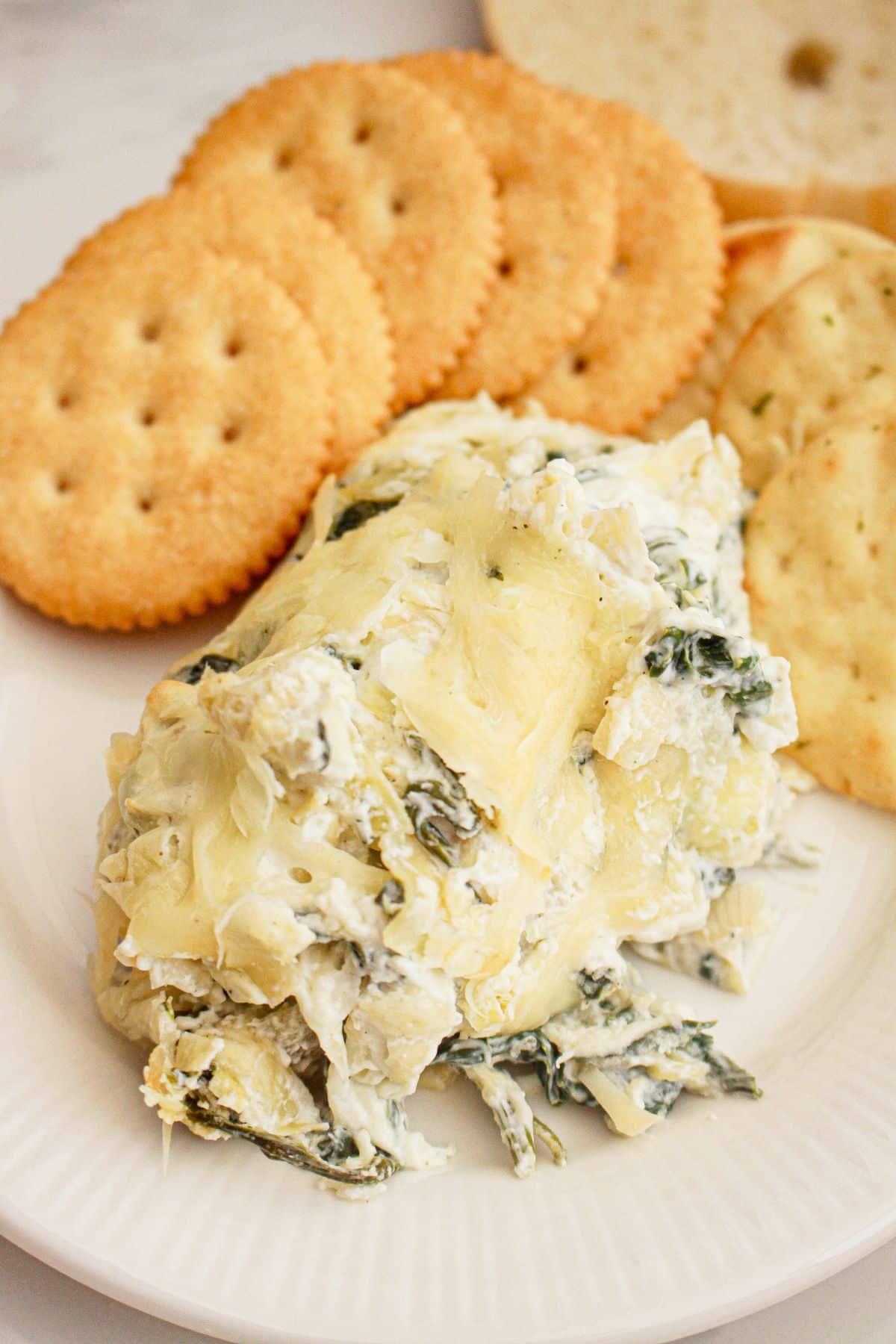 Spinach dip on a plate with crackers.