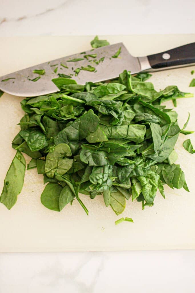 Spinach being chopped on a cutting board.