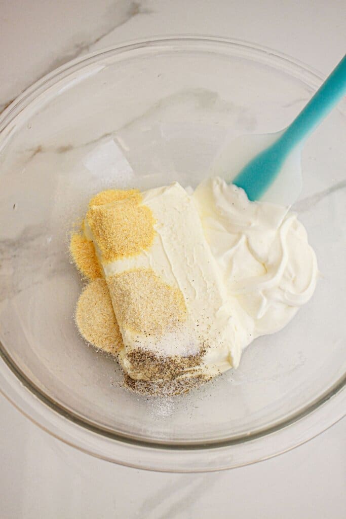 Cream cheese and seasonings being mixed together in a bowl.