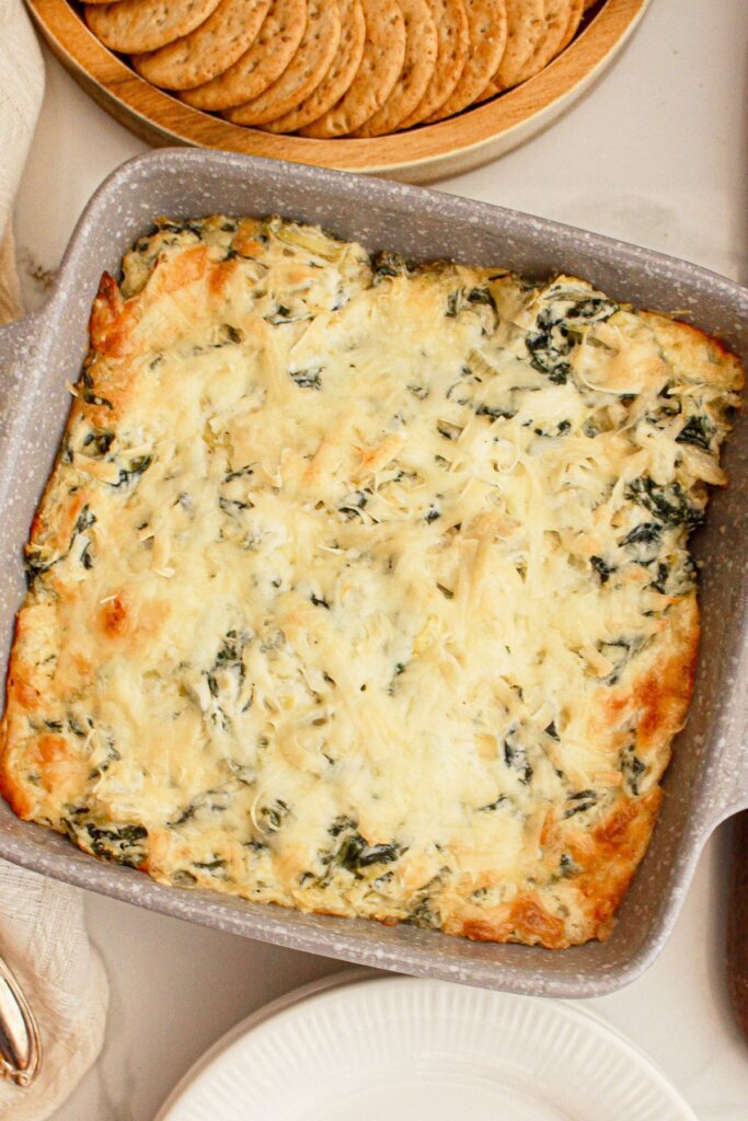 Casserole dish full of baking spinach artichoke dip.