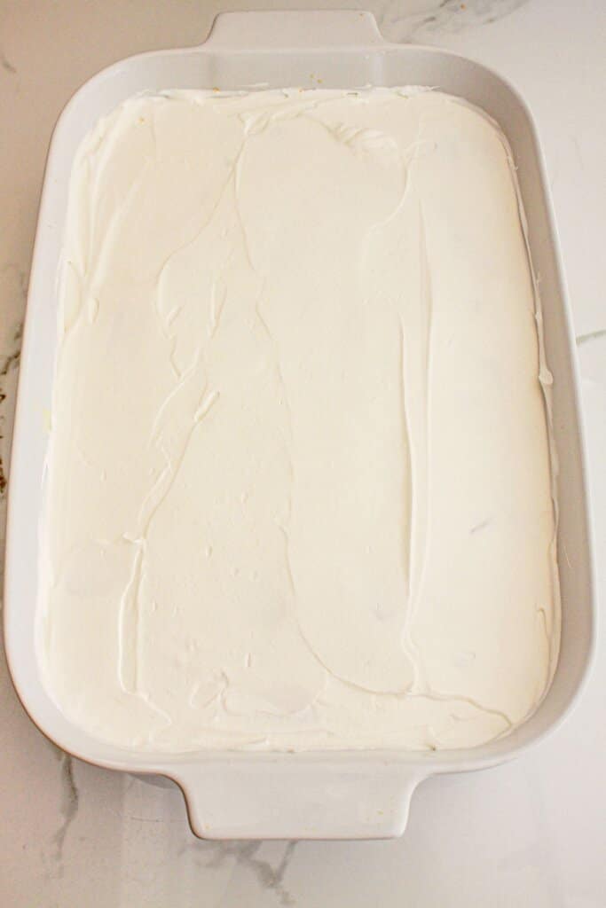 Cool Whop being spread on top of dessert in a baking dish.