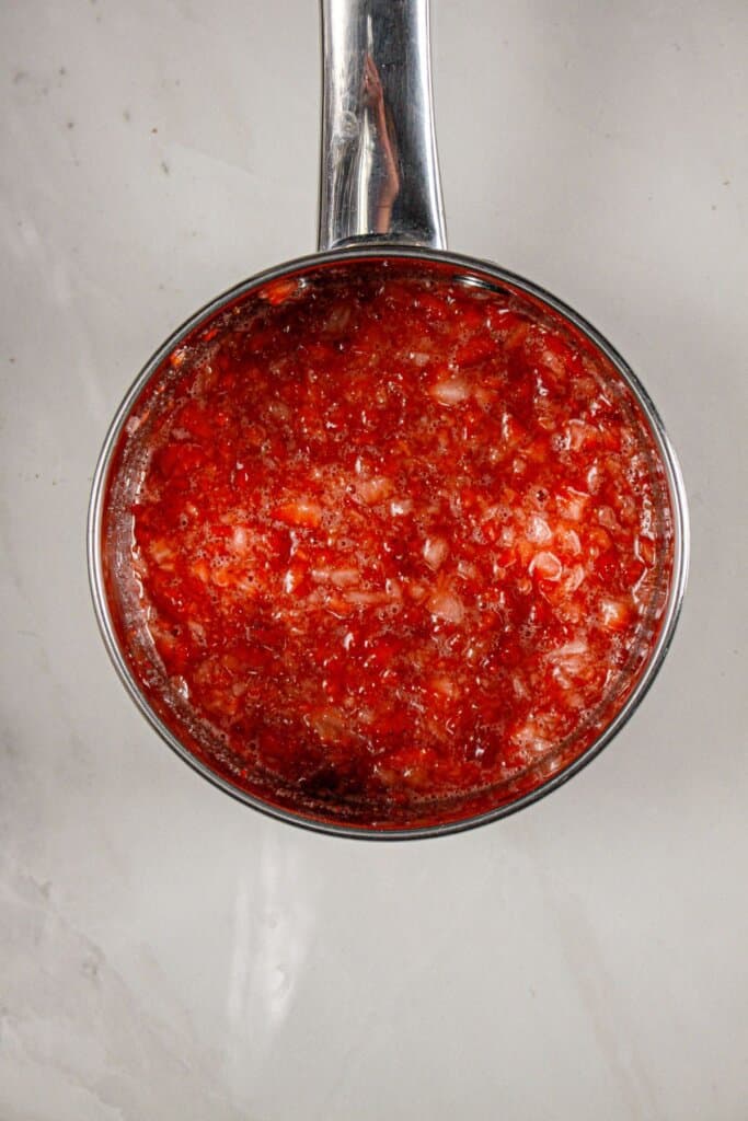 Strawberry gelatin being cooked in a saucepan.