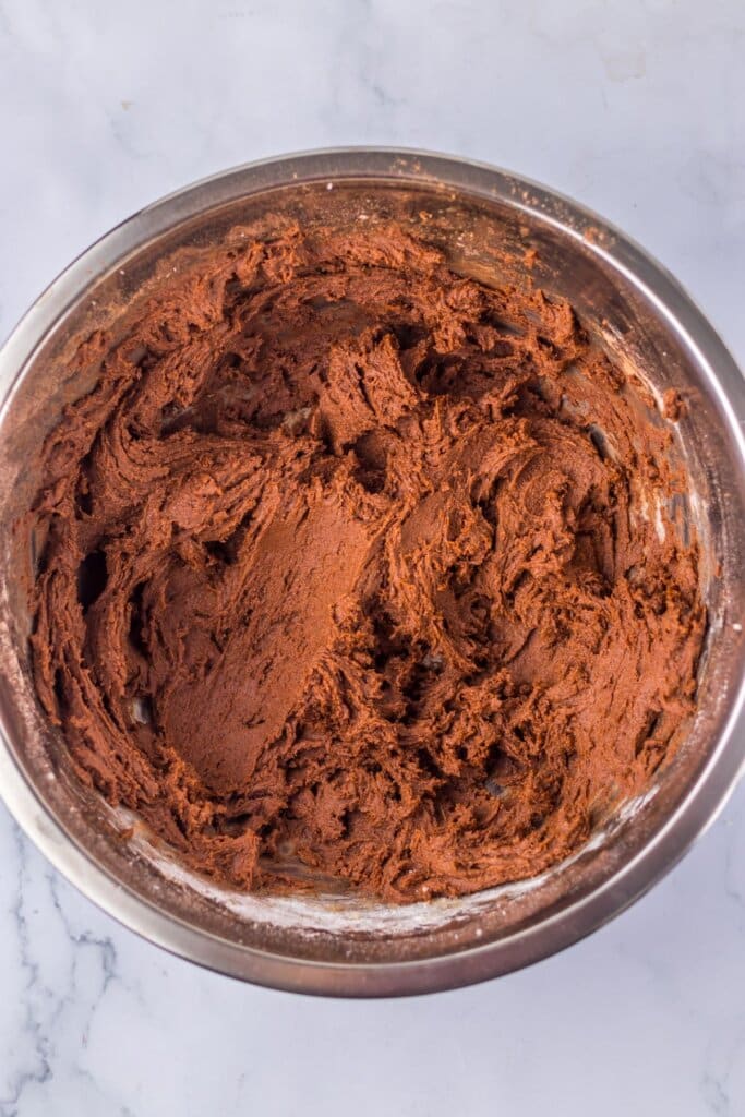 Cookie dough in a stainless steel mixing bowl.