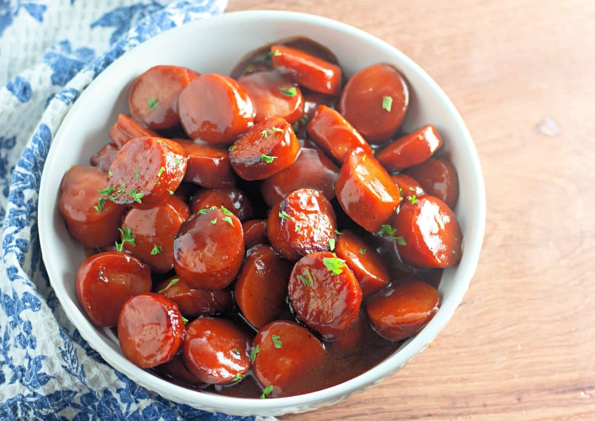 White bowl full of baked bbq kielbasa.