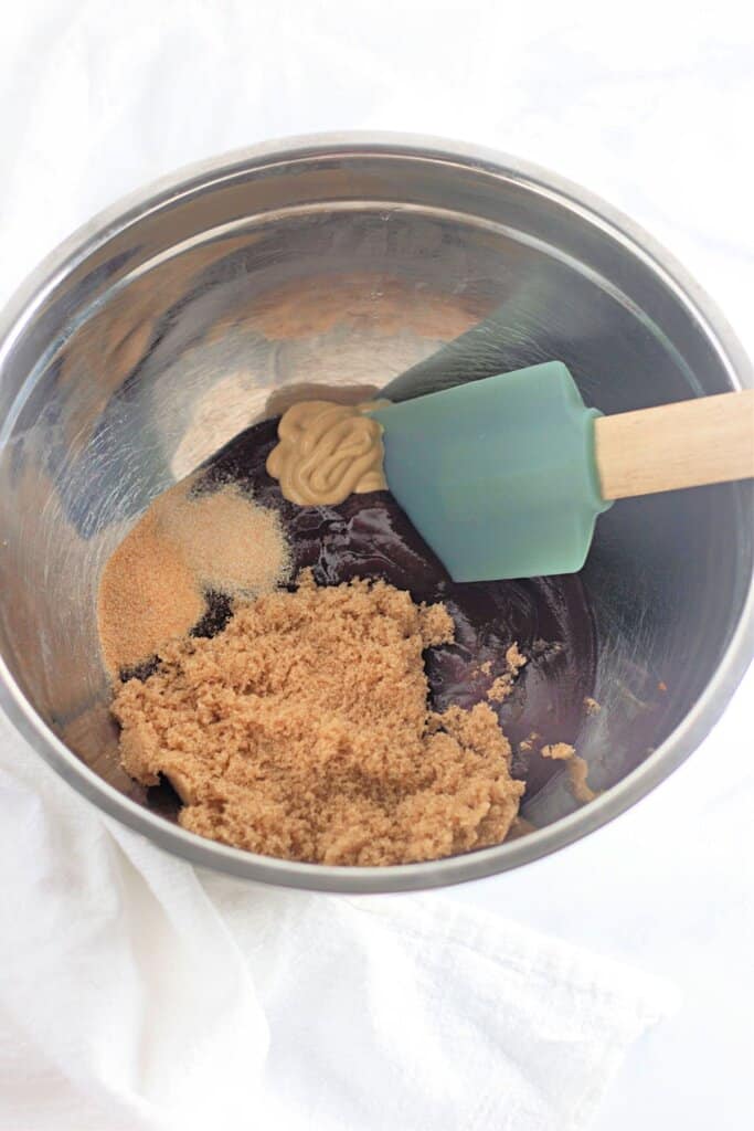 Sauce ingredients in a stainless steel mixing bowl being mixed with a rubber spatula.
