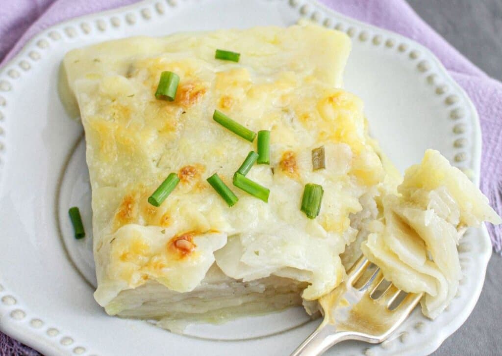 Serving of chive scallopped potatoes on a plate.