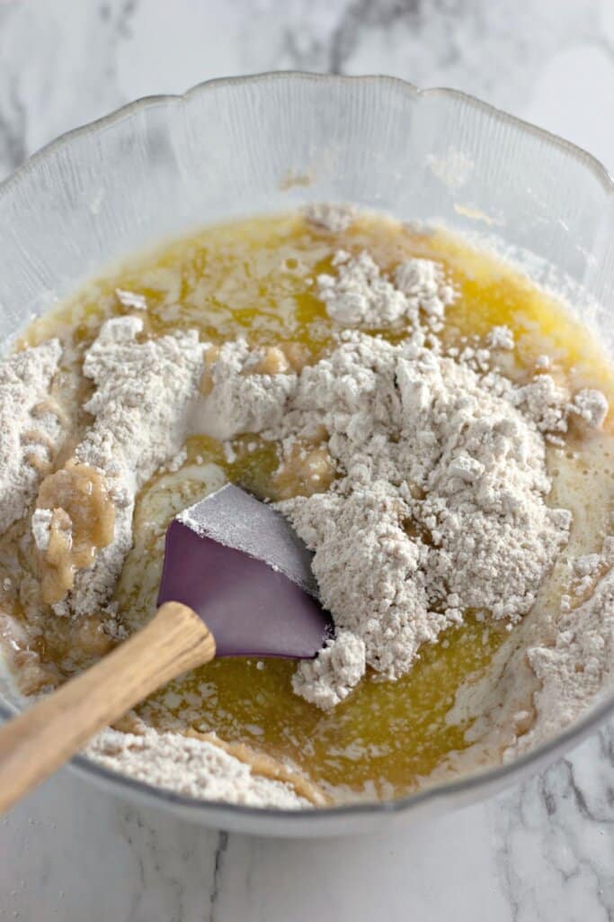 Dry ingredients being added to wet ingredients in a mixing bowl.