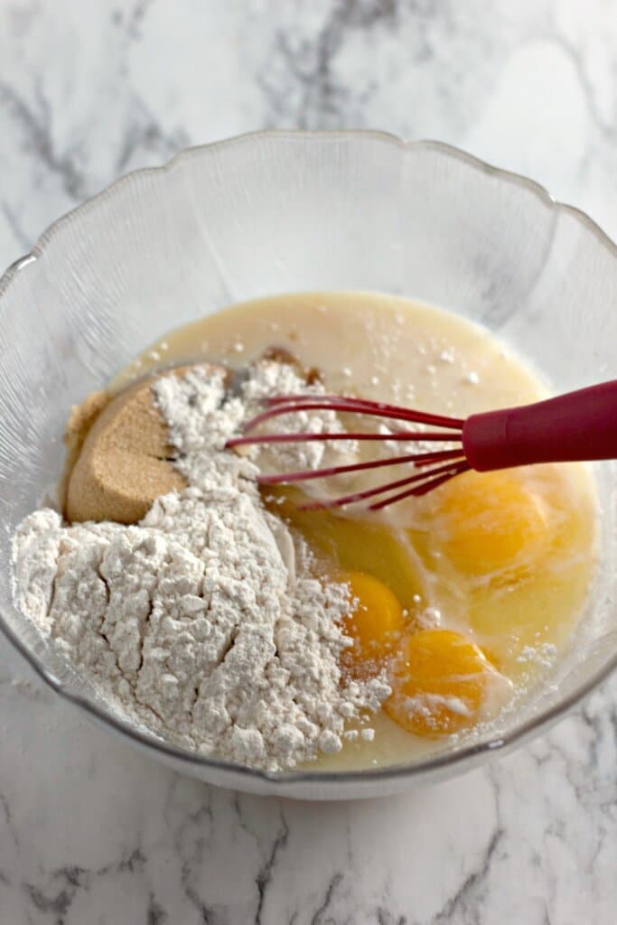 Flour and eggs being added to batter in a large bowl.