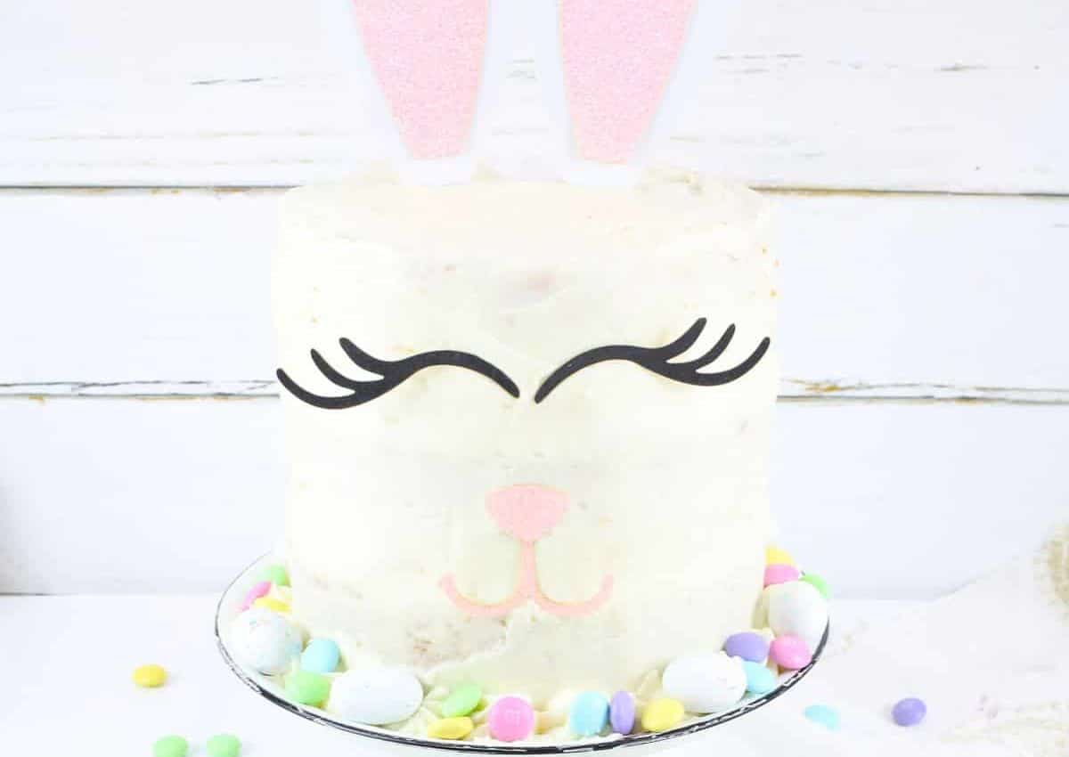 Easter bunny cake on a plate surrounded by easter candy.