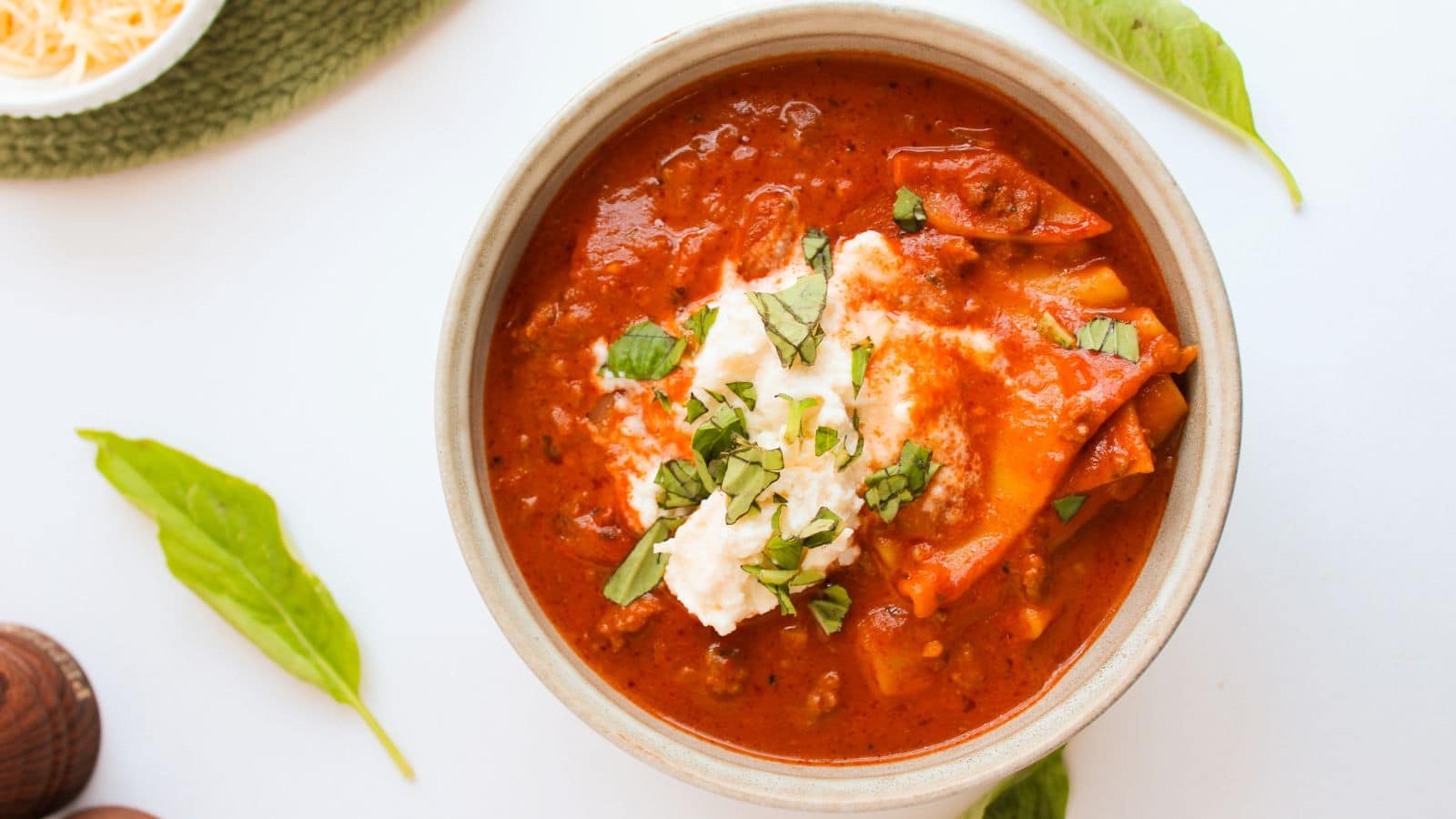 Bowl full of lasagna soup and topped with a ricotta and parmesan mixture.