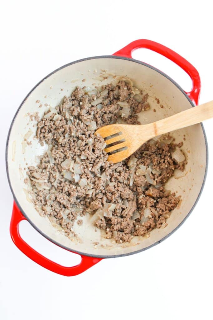 Beef and onions being cooked in a large pot.