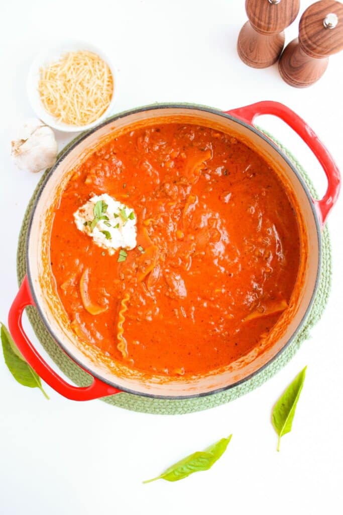 Dutch oven full of lasagna soup and topped with ricotta.