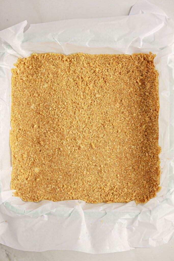 Graham cracker crust in a parchment lined baking dish.