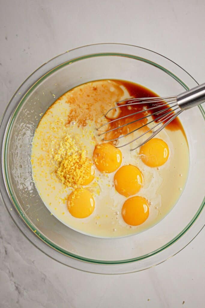 Eggs, zest, vanilla, and condensed milk in a large glass bowl.