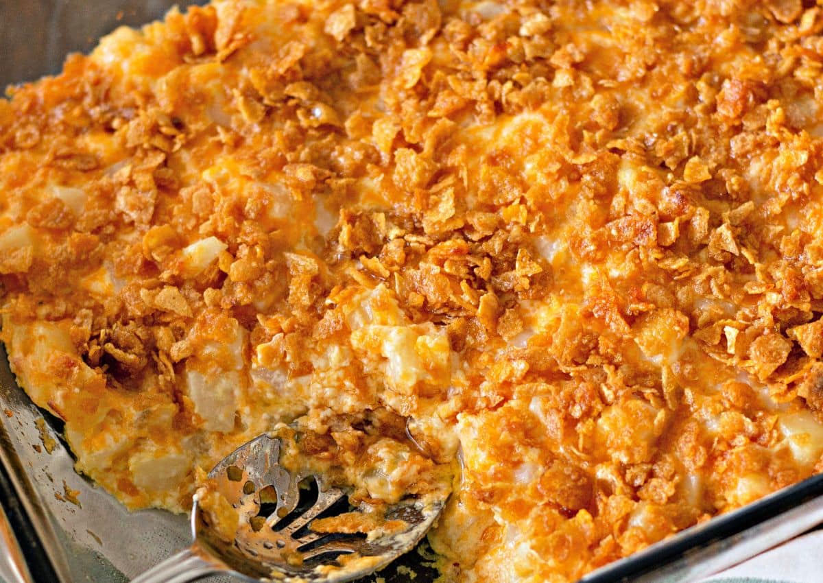 Spoonful of funeral potatoes being removed from a casserole.