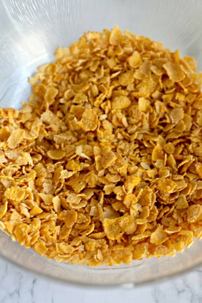 Corn flakes and melted butter being mixed together.