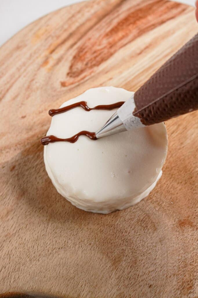 Chocolate being piped on top of a dessert.