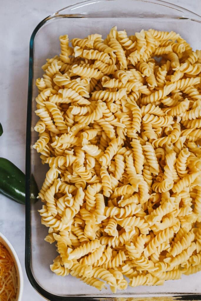 Pasta being added to a casserole dish.