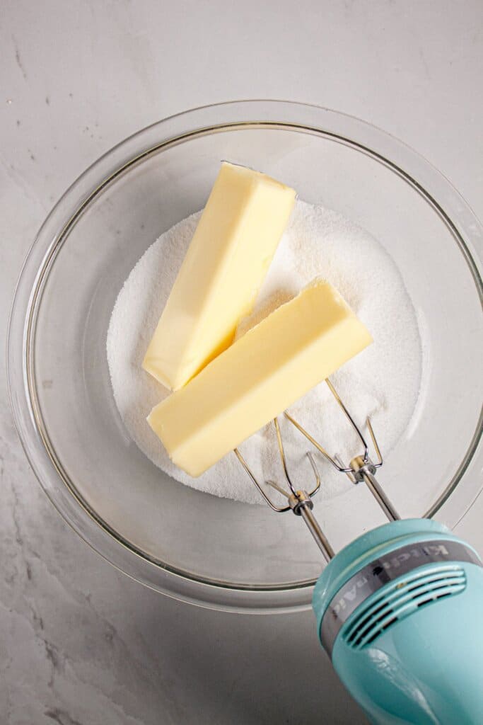 Butter and sugar being mixed in a glass bowl.