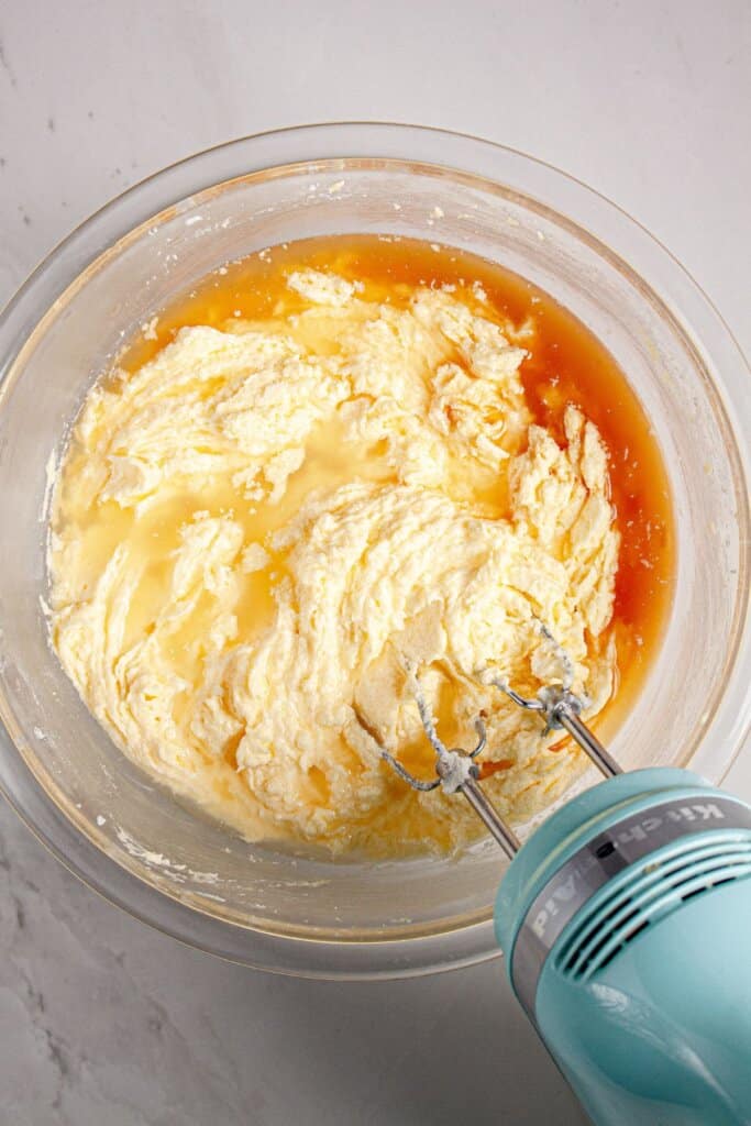 Eggs and vanilla being added to batter in a glass bowl.