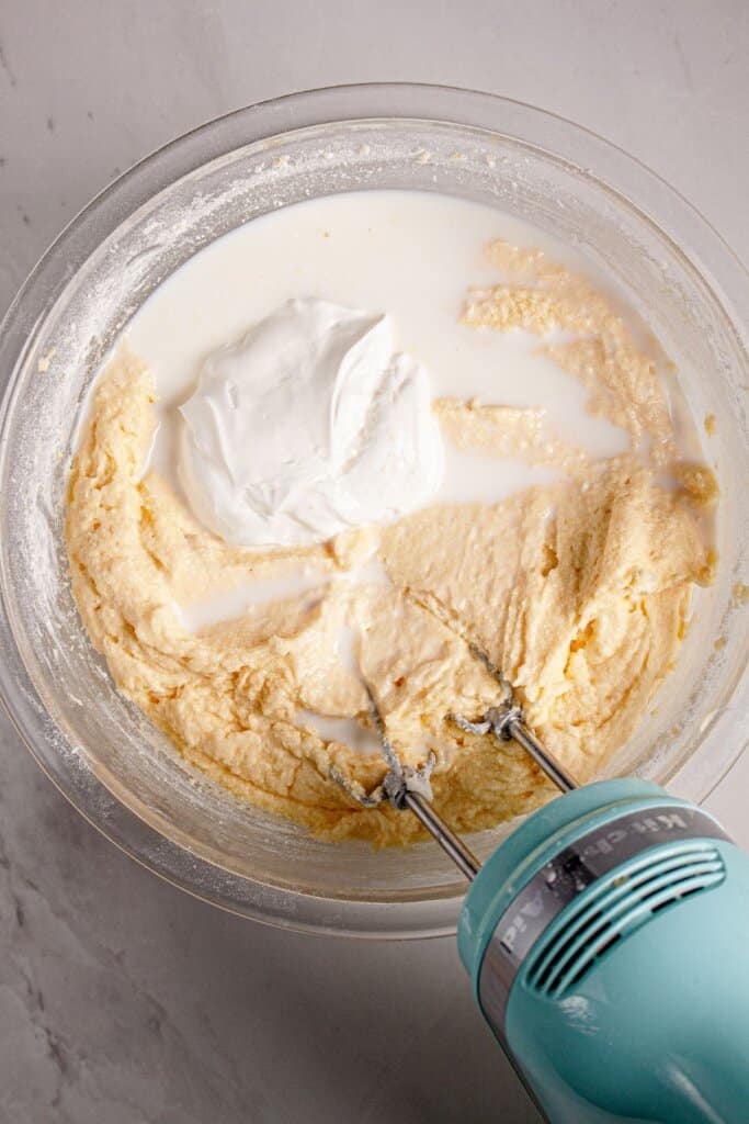 Yogurt being added to batter in a glass mixing bowl.