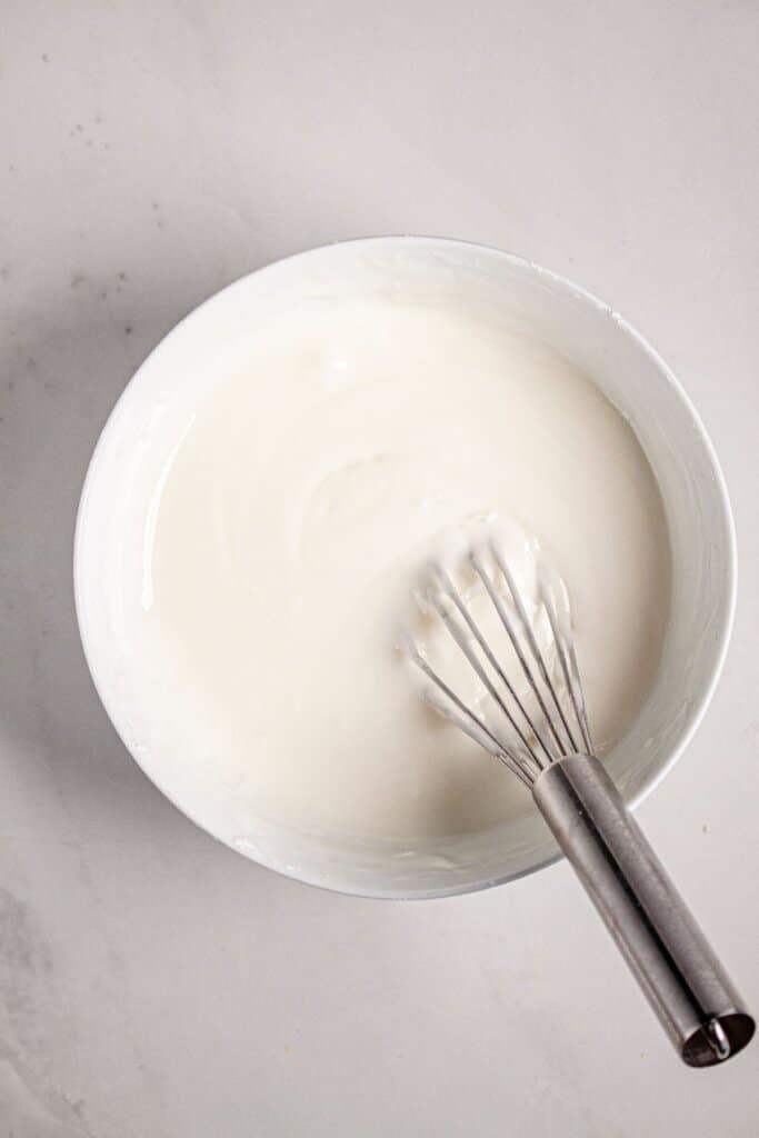 Glaze being mixed in a small bowl with a whisk.