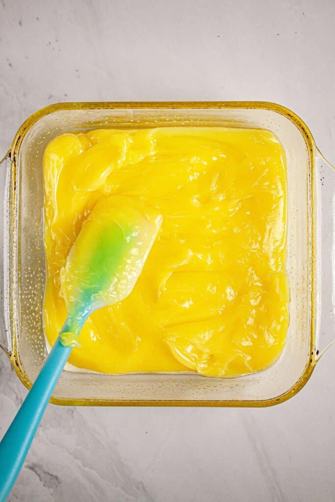 Lemon filling being spread into a baking dish.