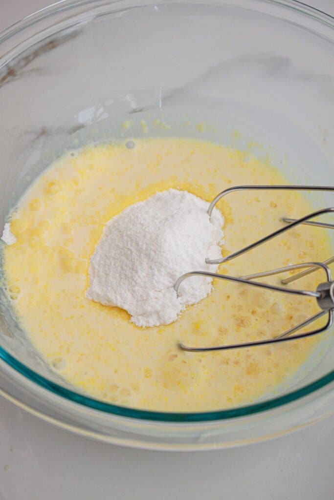 Pudding being added to milk in a glass bowl.