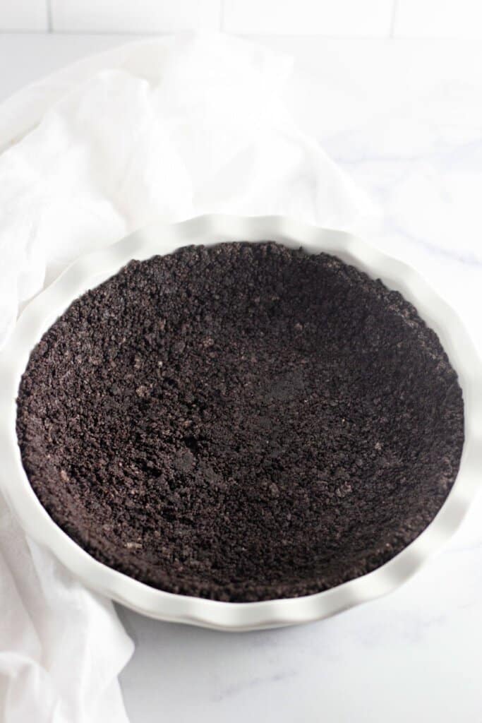 Crust being pressed firmly into a baking dish.
