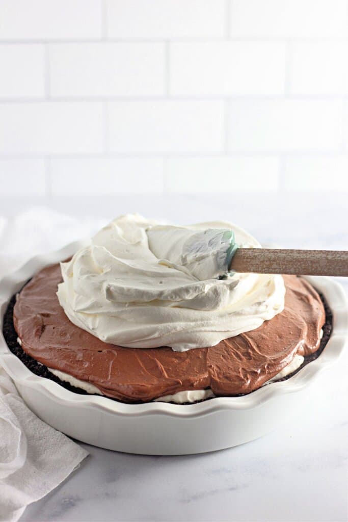 Whipped cream being spread on top of a pie.