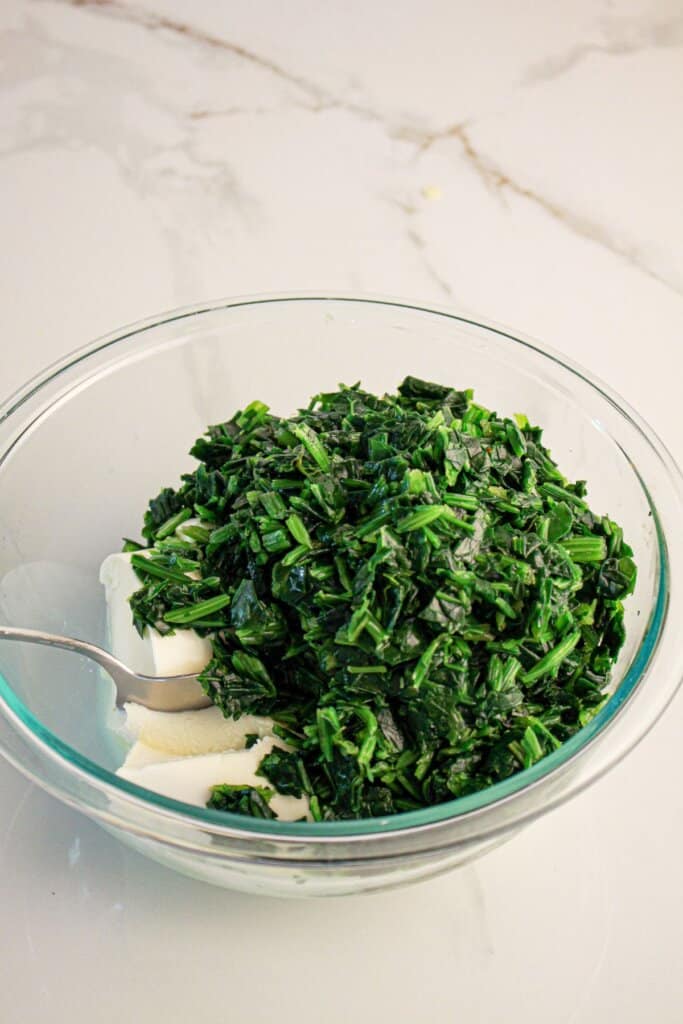 Spinach and ricotta being mixed together in a small bowl.