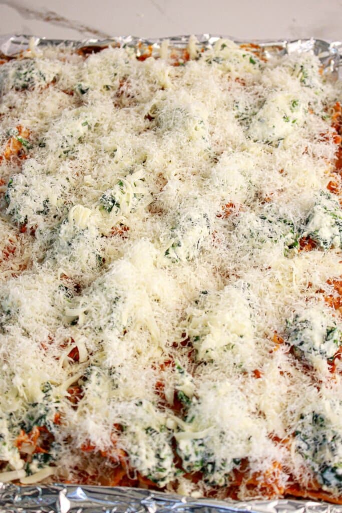 Mozzarella cheese being sprinkled on top of pan.