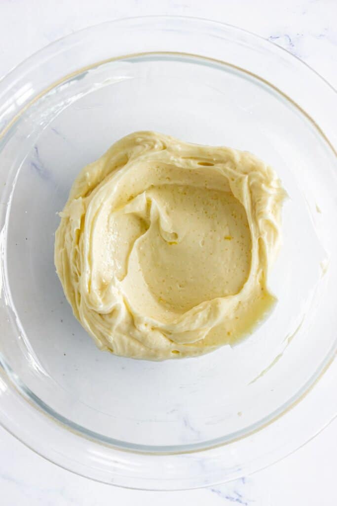 Cream cheese and egg being mixed in a glass bowl.
