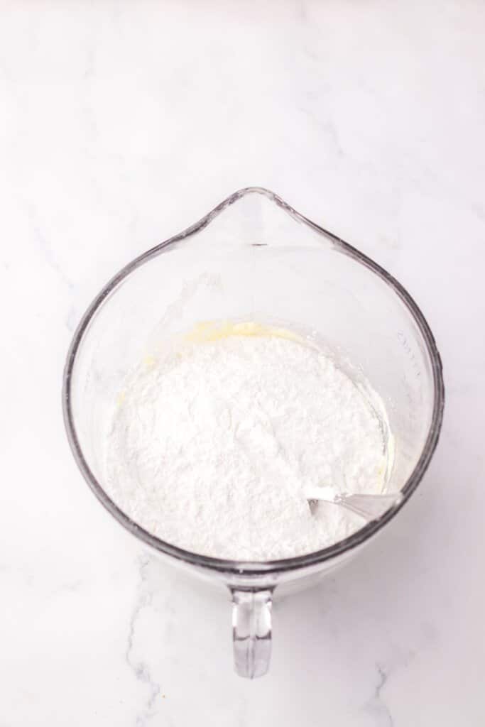 Powdered sugar and cream cheese in a mixing bowl.